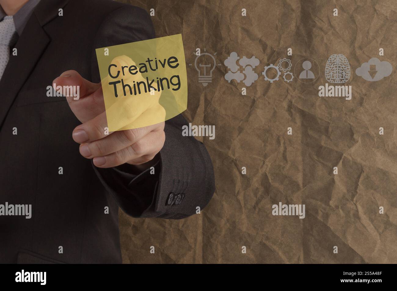 Imprenditore punto a mano il pensiero creativo su una nota adesiva con icone accartocciata riciclare carta background come concetto Foto Stock