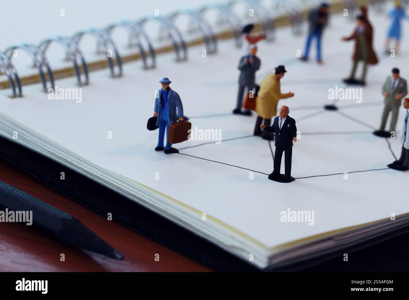 Close up di persone in miniatura con sociale schema di rete sul notebook aperto sulla scrivania di legno come i social media concept Foto Stock