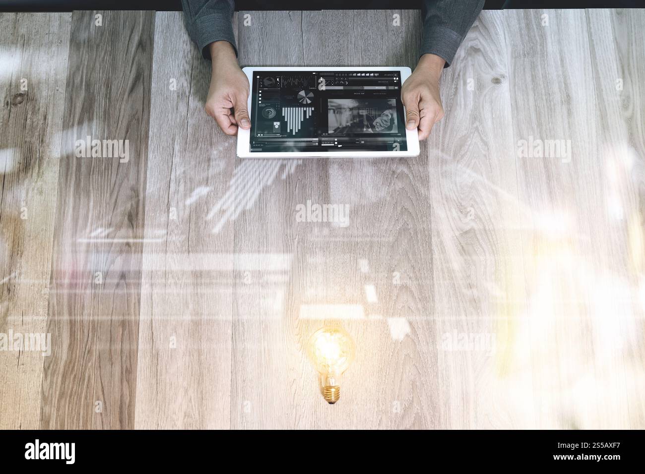 Lavoro creativo. Designer grafico fotografico che lavora a mano con tablet digitale di design e lampadina a luce fissa su un tavolo in legno. Strategia aziendale digitale Foto Stock