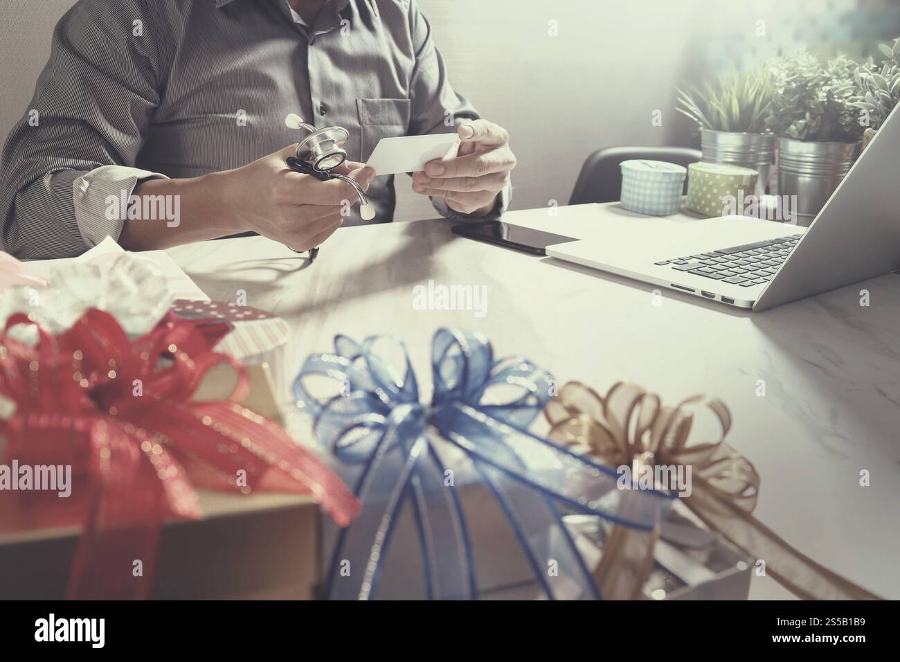 Dono, medico mano con carta di credito e mano con regalo. Consegna in omaggio, sorpresa, computer portatile e smartphone sulla scrivania Mable, vintage Foto Stock