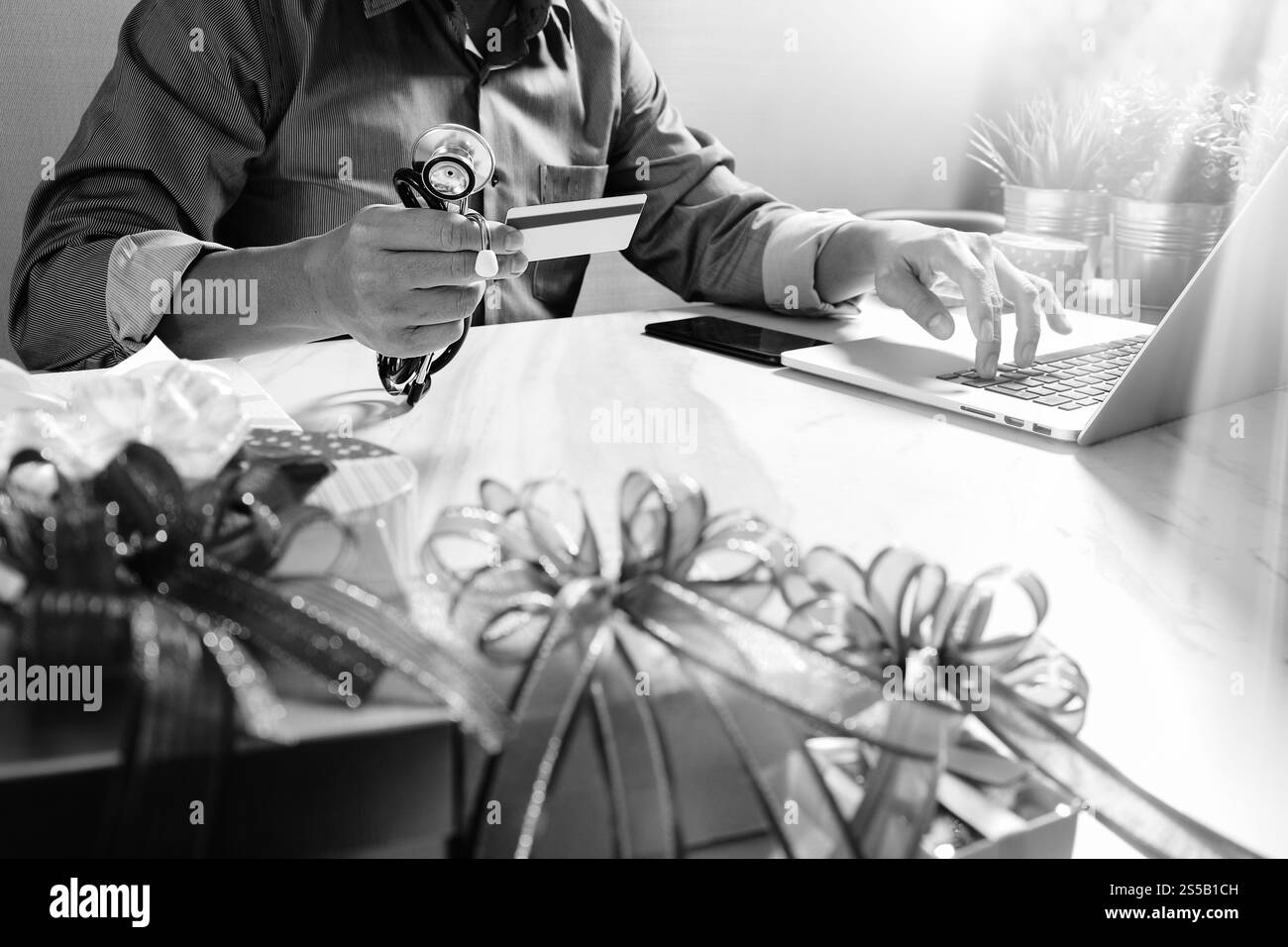 Dono, medico mano con carta di credito e mano con regalo. Consegna regalo, sorpresa, computer portatile e smartphone sulla scrivania, nero e Foto Stock