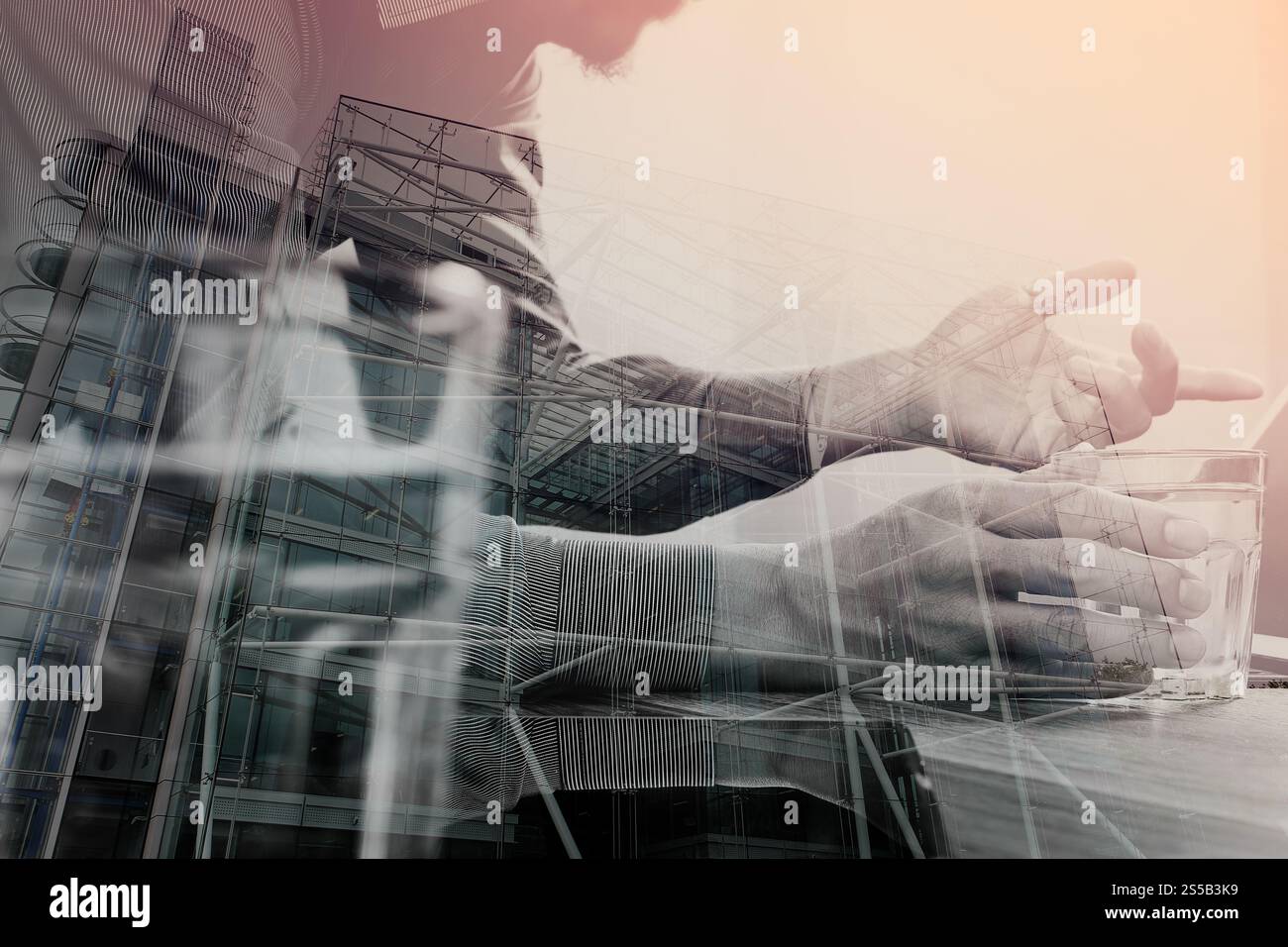 Doppia esposizione del designer del sito Web che tiene mano un tablet digitale e un computer portatile su una scrivania in legno, architettura londinese Foto Stock