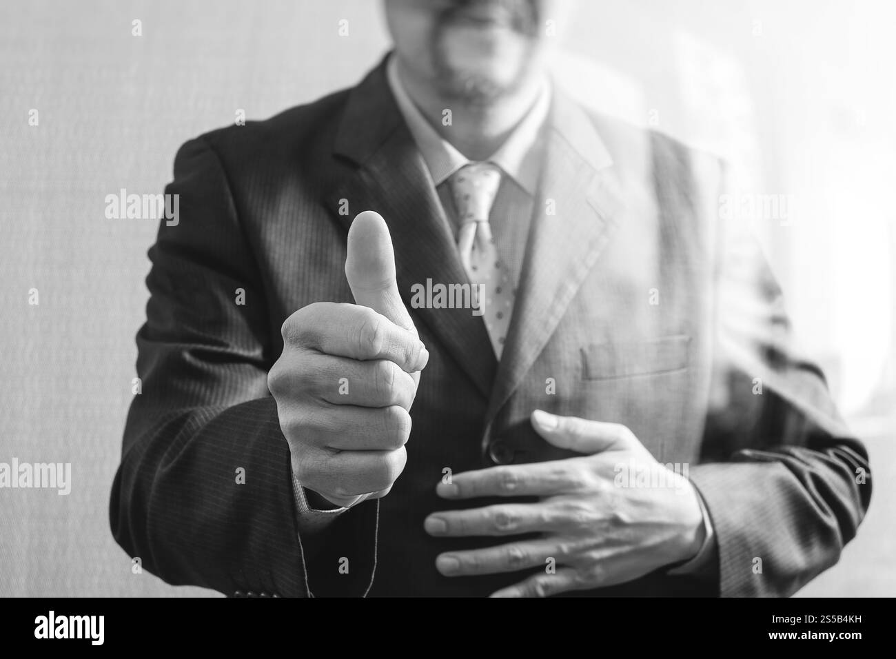 Imprenditore con il suo pollice in alto vista frontale, senza testa. Concetto di lavoro in un ufficio.bianco nero Foto Stock
