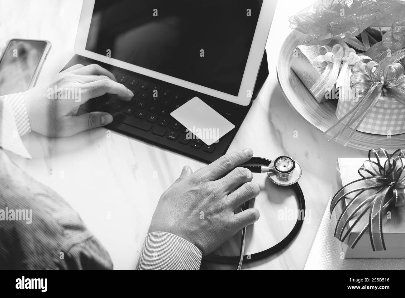 Dono, medico mano con carta di credito e mano con regalo. Consegna regalo, sorpresa, docking per tablet con tastiera intelligente e smartphone Foto Stock