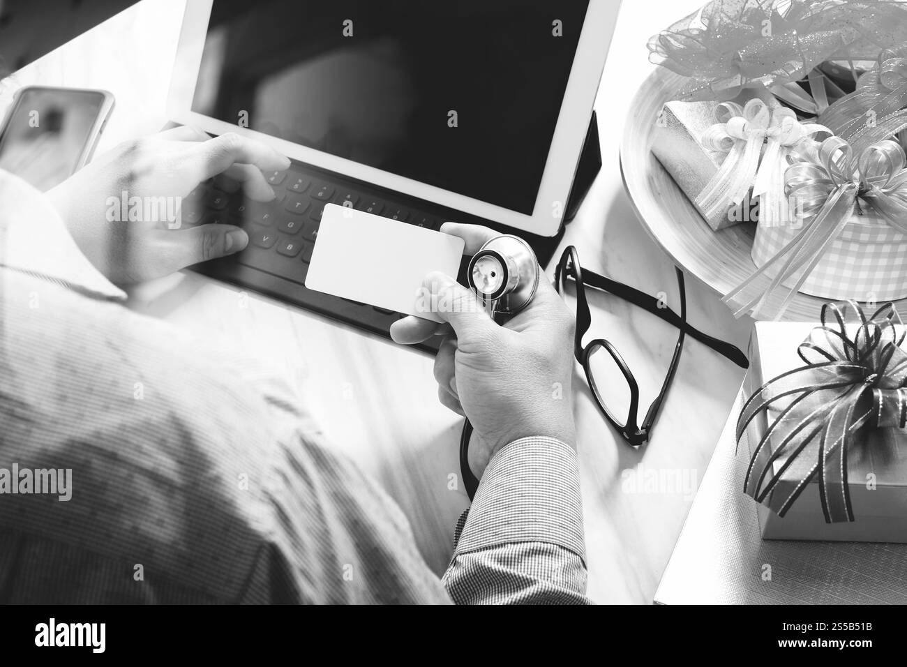 Dono, medico mano con carta di credito e mano con regalo. Consegna regalo, sorpresa, docking per tablet con tastiera intelligente e smartphone Foto Stock