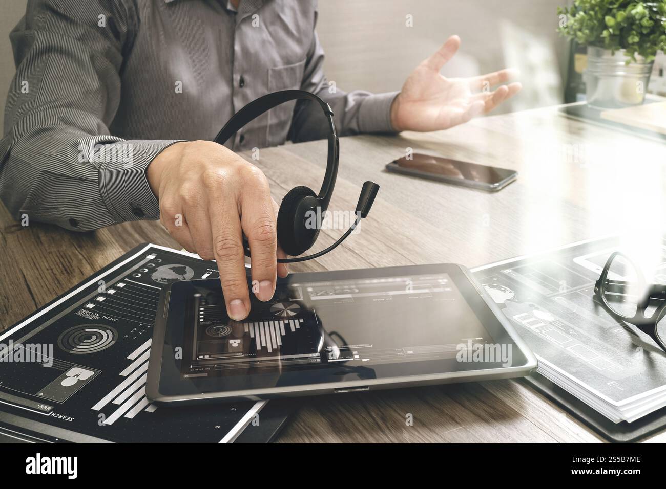 Uomo d'affari che utilizza una cuffia VoIP con un tablet digitale, documenti, comunicazioni concettuali, supporto IT, call center e assistenza clienti Foto Stock