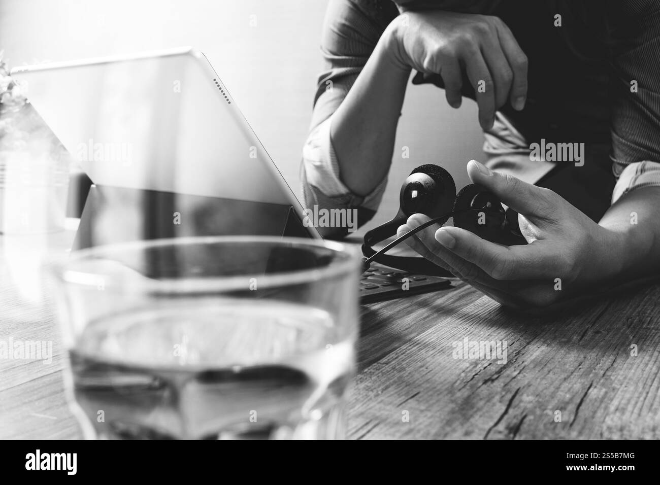 Business man utilizzando cuffie VOIP con tavoletta digitale computer docking tastiera intelligente, il concetto di comunicazione, il supporto it,sulla scrivania di legno,bianco nero Foto Stock