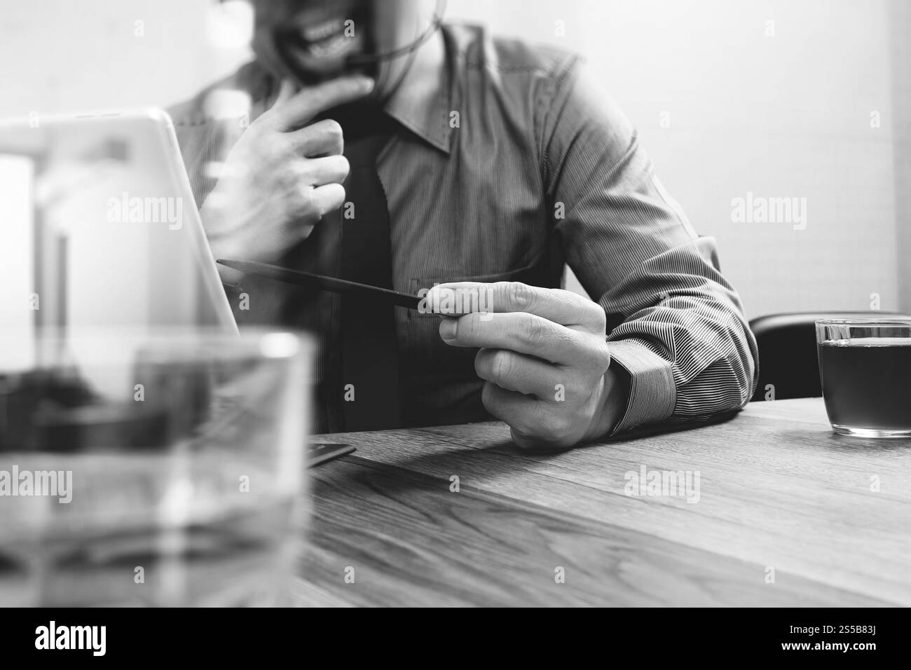 Business man utilizzando cuffie VOIP con tavoletta digitale computer docking tastiera intelligente, il concetto di comunicazione, il supporto it,sulla scrivania di legno,bianco nero Foto Stock