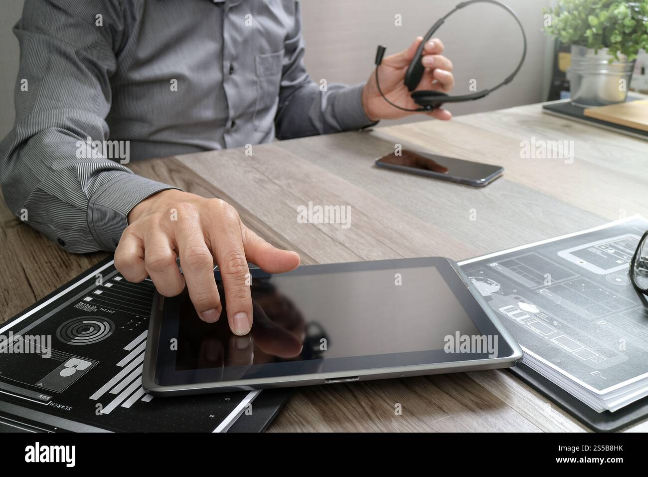 Uomo d'affari che utilizza una cuffia VoIP con un tablet digitale, documenti, comunicazioni concettuali, supporto IT, call center e assistenza clienti Foto Stock