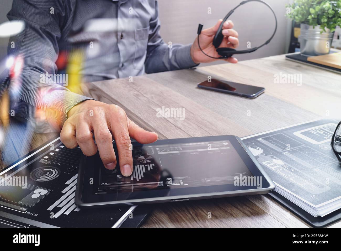 Uomo d'affari che utilizza una cuffia VoIP con un tablet digitale, documenti, comunicazioni concettuali, supporto IT, call center e assistenza clienti Foto Stock