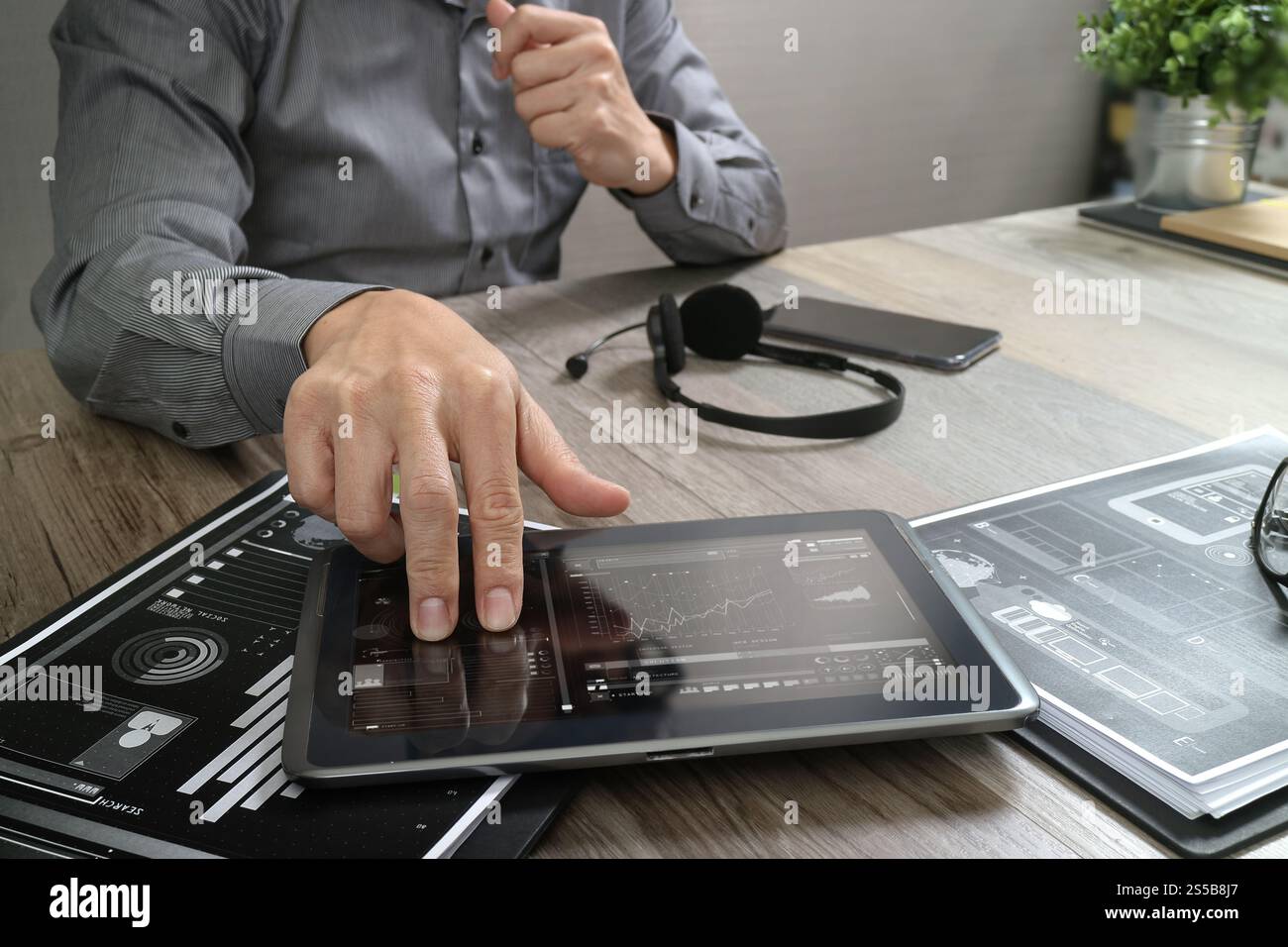 Uomo d'affari che utilizza una cuffia VoIP con un tablet digitale, documenti, comunicazioni concettuali, supporto IT, call center e assistenza clienti Foto Stock