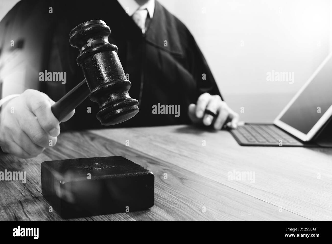 concetto di giustizia e diritto. Giudice maschile in un'aula di tribunale che colpisce il martelletto, lavora con tablet digitale computer docking tastiera su tavolo di legno, nero e. Foto Stock