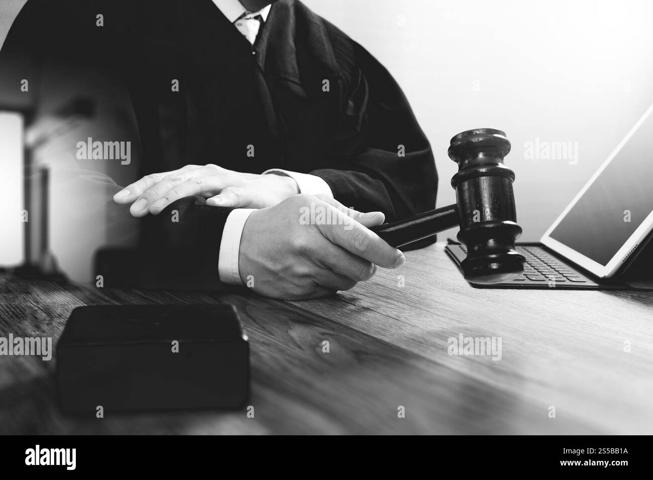 La giustizia e la nozione di diritto.Giudice maschi nelle aule di un tribunale con il martello,lavora con tavoletta digitale computer tastiera docking sulla tavola di legno,in bianco e nero Foto Stock