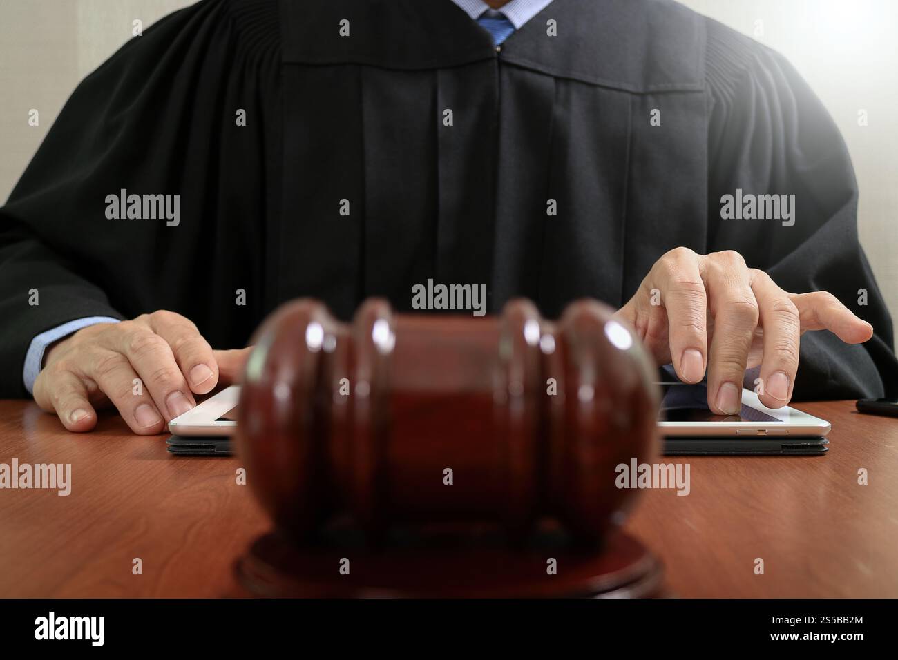 La giustizia e la nozione di diritto.Giudice maschi nelle aule di un tribunale che colpisce il martello,lavora con tavoletta digitale computer tastiera docking sulla tavola di legno Foto Stock