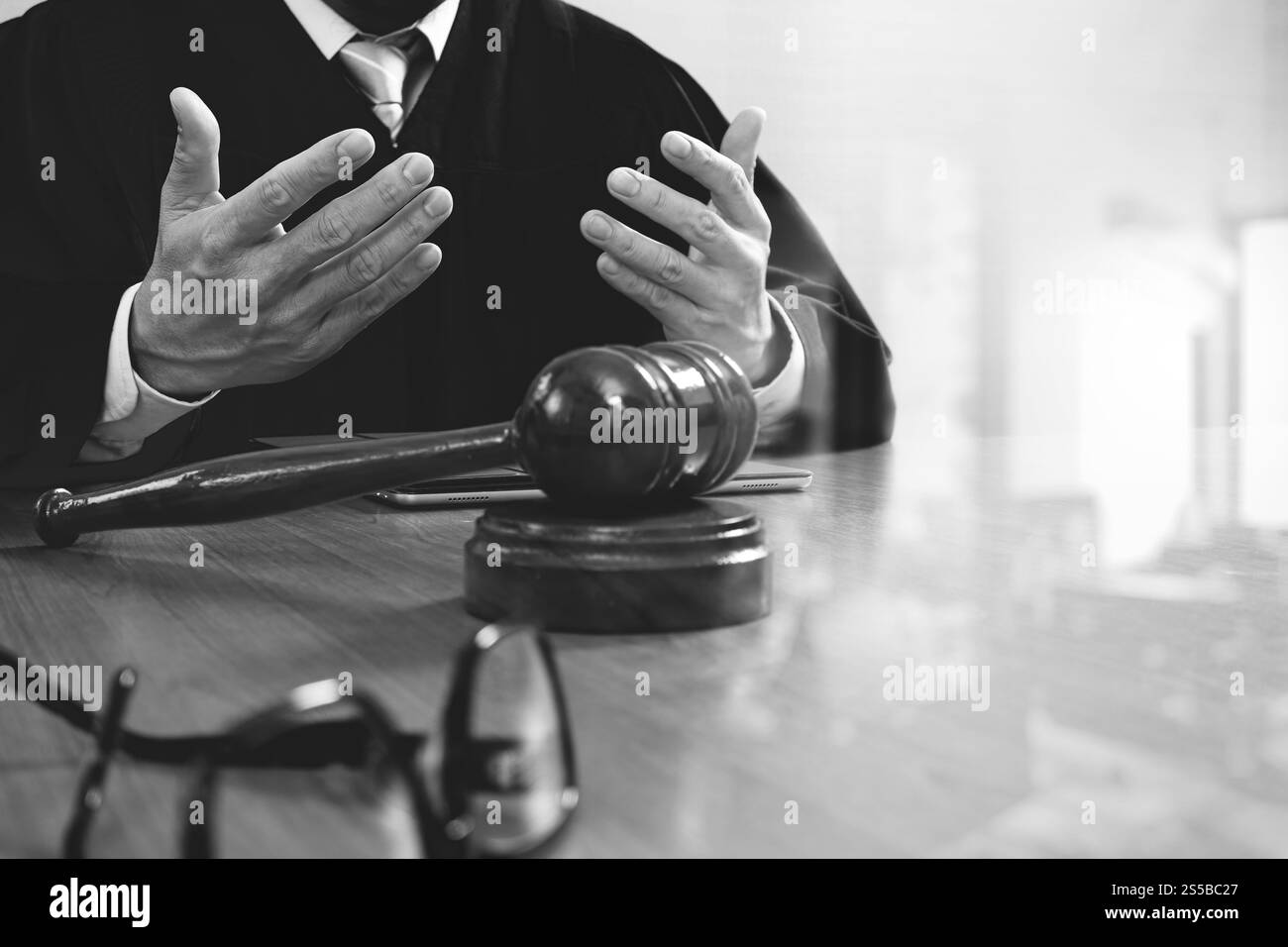 La giustizia e la nozione di diritto.Giudice maschi nelle aule di un tribunale con il martello,lavora con smart phone,digital computer tablet tastiera docking,occhiali,su legno Foto Stock