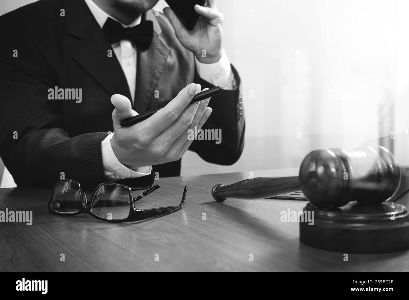 concetto di giustizia e diritto. Avvocato maschile in ufficio con il martelletto, lavorare con smartphone, tablet digitale computer docking tastiera, occhiali, su legno Foto Stock