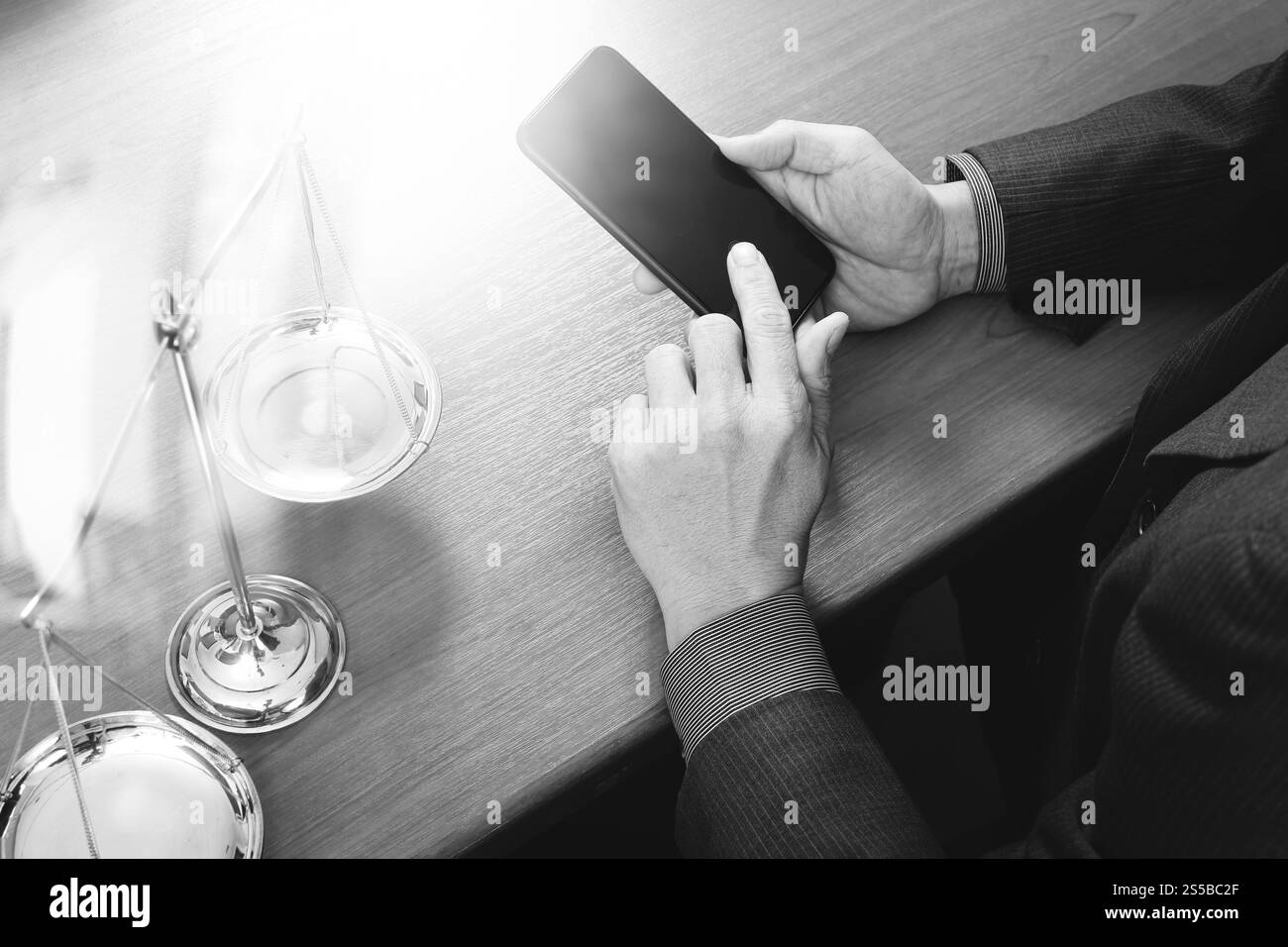 concetto di giustizia e diritto. Avvocato maschile in ufficio con il martelletto, lavorare con smartphone, tablet digitale computer docking tastiera, bilancia in ottone, su legno Foto Stock