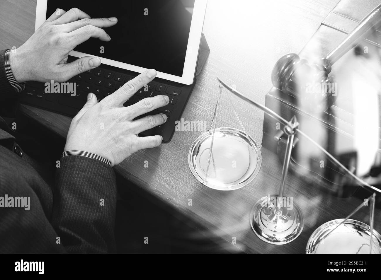 concetto di giustizia e diritto. Avvocato maschile in ufficio con il martelletto, lavorare con smartphone, tablet digitale computer docking tastiera, bilancia in ottone, su legno Foto Stock