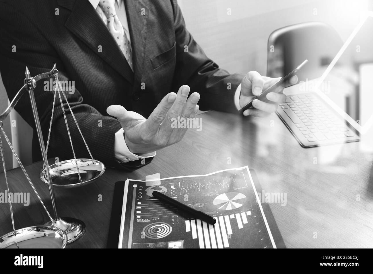 concetto di giustizia e diritto. Avvocato maschile in ufficio con il martelletto, lavorare con smartphone, tablet digitale computer docking tastiera, bilancia in ottone, su legno Foto Stock