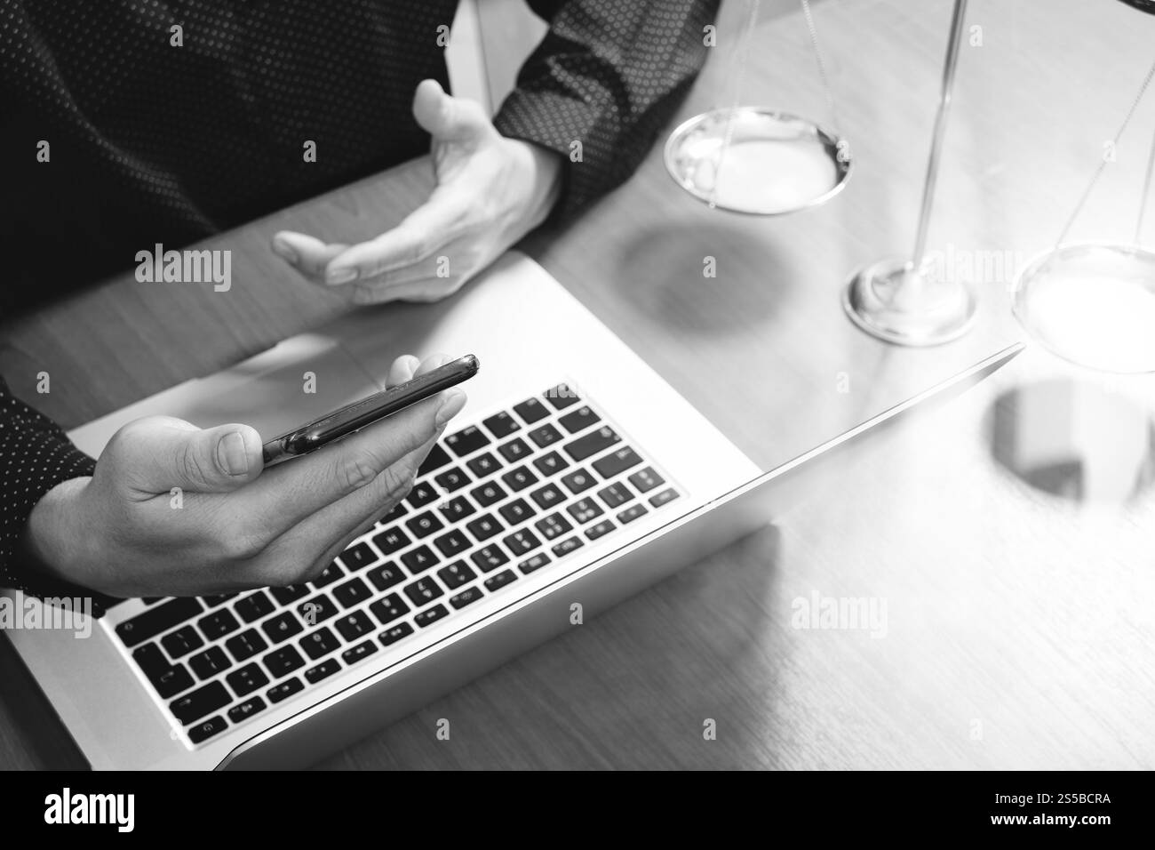 concetto di giustizia e diritto. Avvocato maschile in ufficio con il martelletto, lavorare con smartphone, tablet digitale computer docking tastiera, bilancia in ottone, su legno Foto Stock