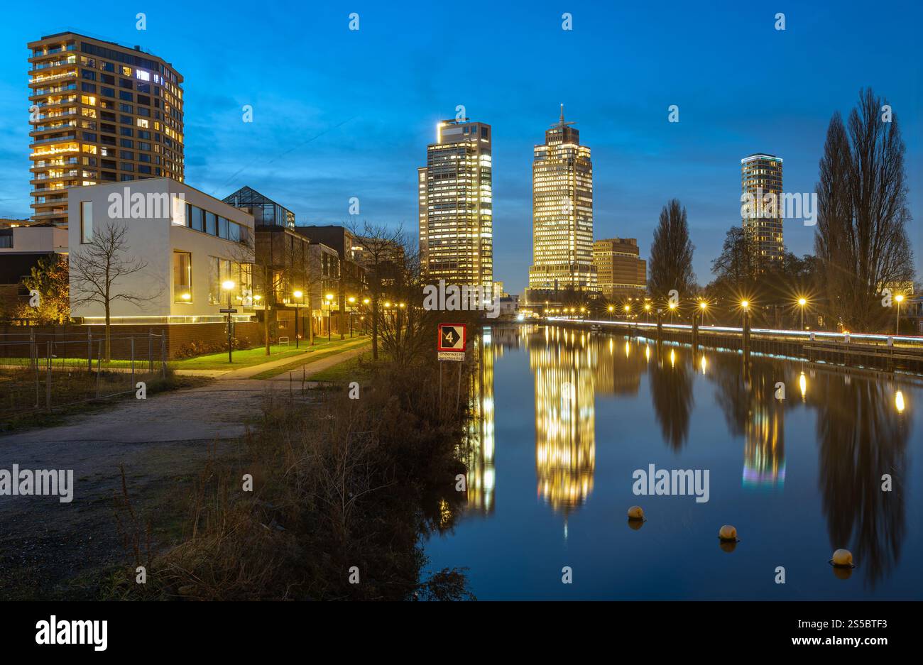 Lo skyline di Amsterdam di notte, i grattacieli del quartiere Omval si specchiano sul canale Weespertrekvaart Foto Stock