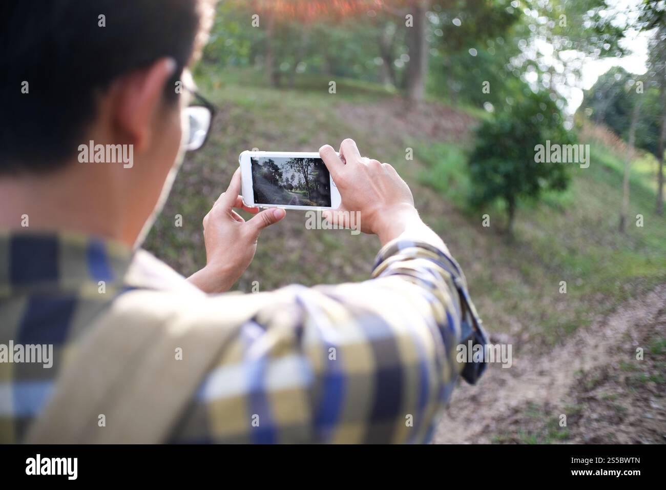 Giovane che scatta foto con il suo telefono della vista sulle montagne Foto Stock