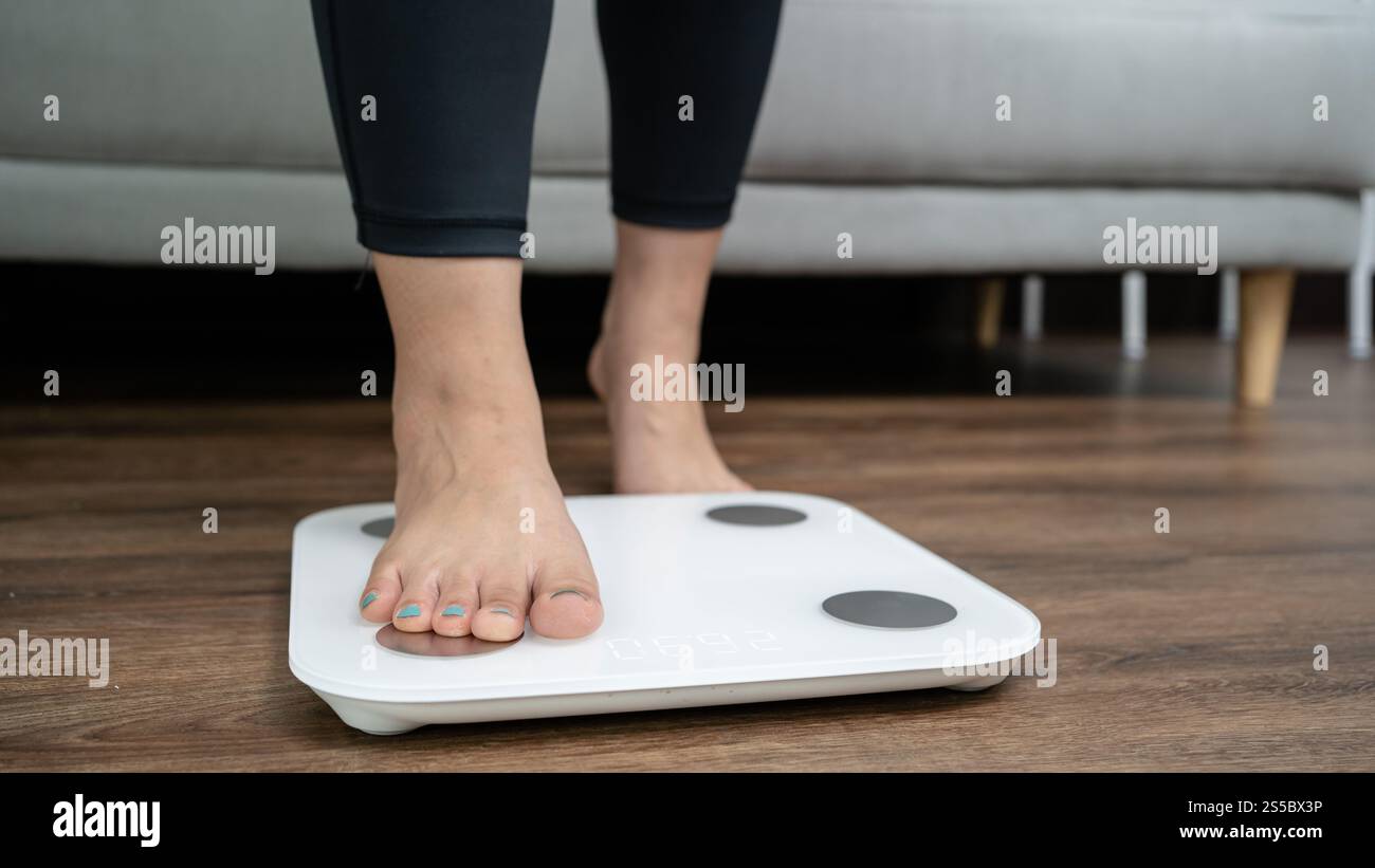 piedi in piedi su bilance elettroniche per il controllo del peso. Strumento di misurazione in chilogrammi per il controllo della dieta. Foto Stock