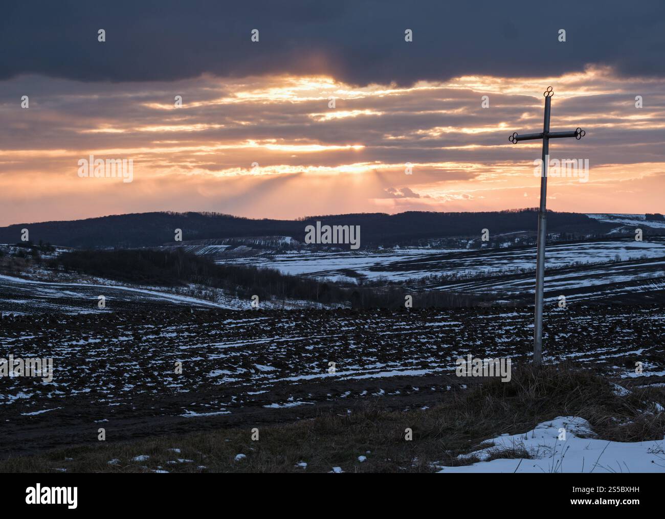 Terra nera, terra arabile coperta dall'ultima neve, primavera primaverile. Calmo tramonto serale nella campagna Ucraina, regione di Lviv. Foto Stock