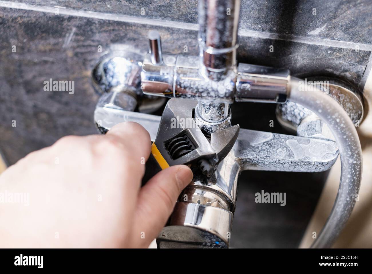 l'idraulico fissa il dado del rubinetto della doccia vicino in su sulla parete piastrellata nel paese Foto Stock