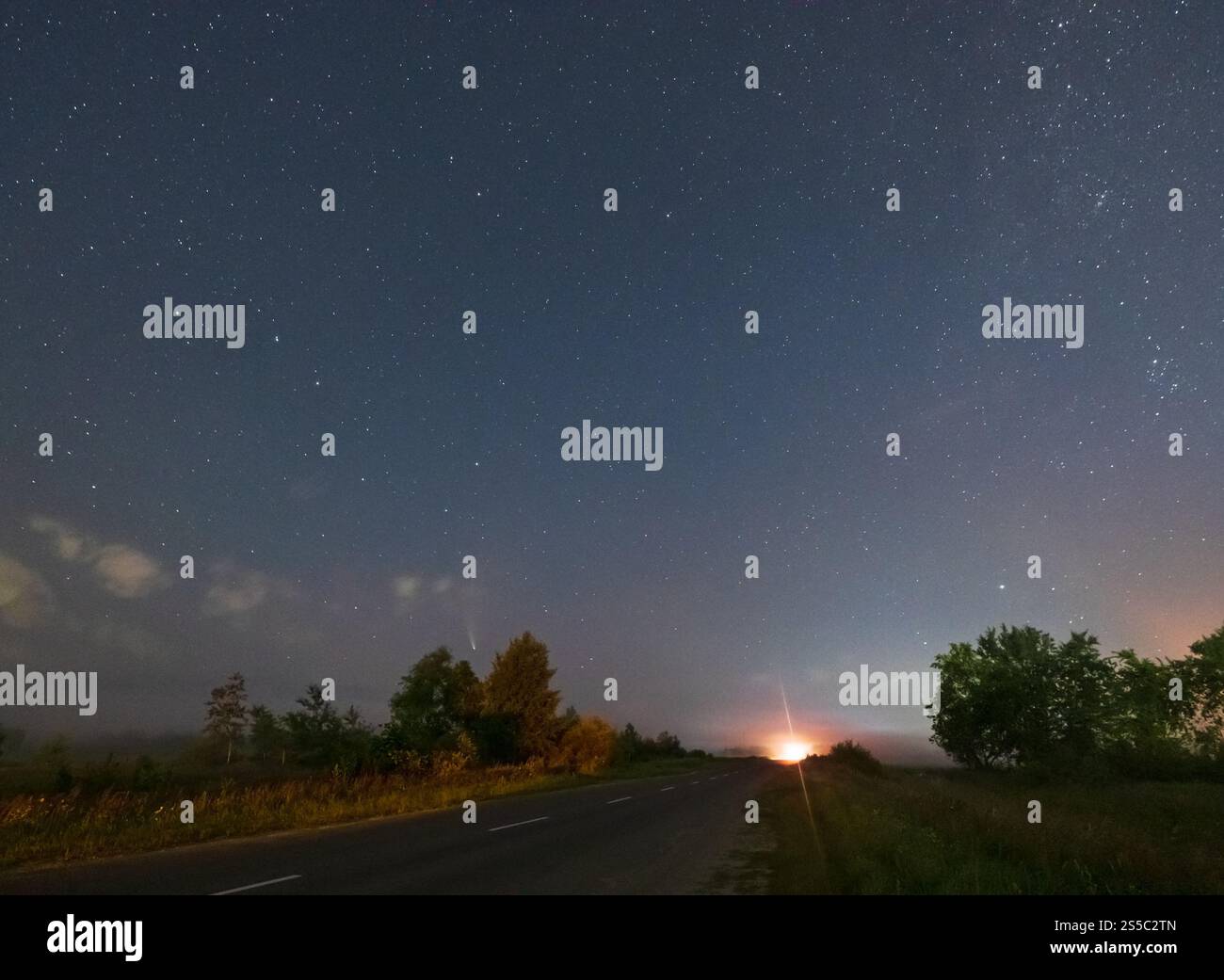 Comet Neowise C2020 F3 come vola in alto nel cielo estivo sopra prato vicino campagna strada, regione Lviv, Ucraina. Foto Stock