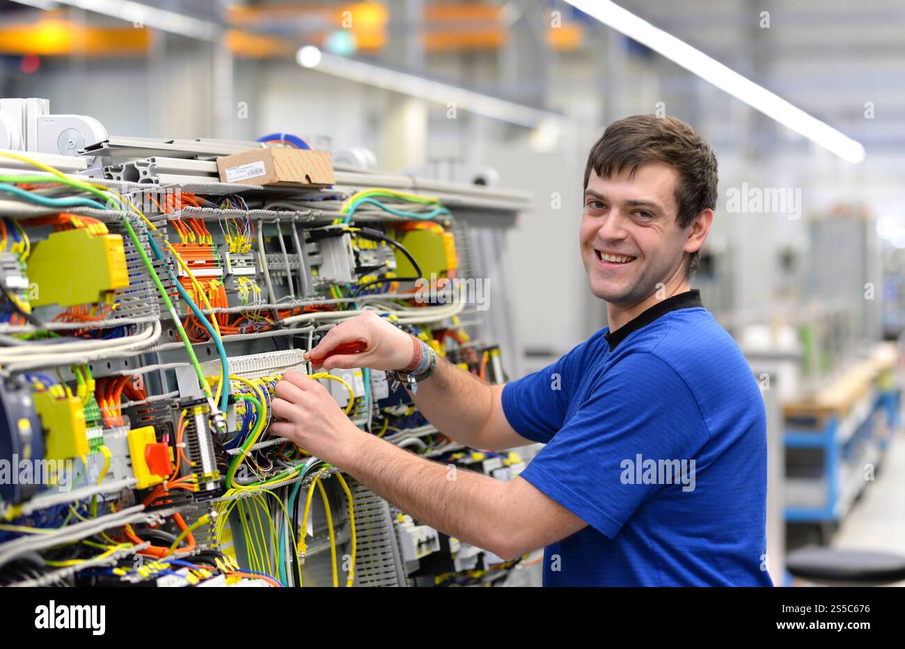 un operatore giovane assembla la macchina in un moderno stabilimento high tech - produzione armadi elettrici per impianti industriali Foto Stock