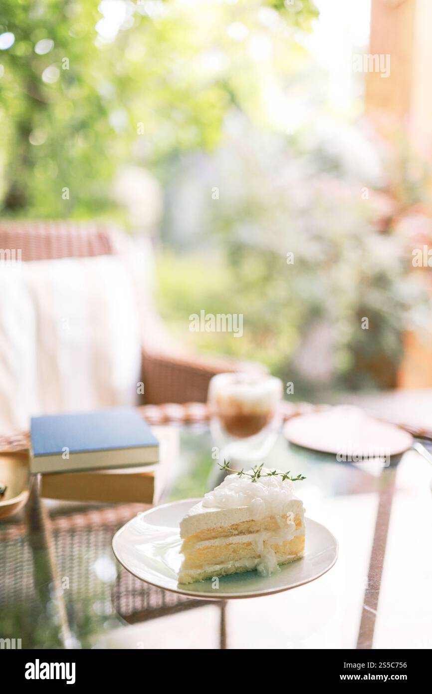 Torta al cocco e caffè in una caffetteria sullo sfondo sfocato. Dessert tradizionale a fette di deliziosa torta a strati di cocco. Foto Stock