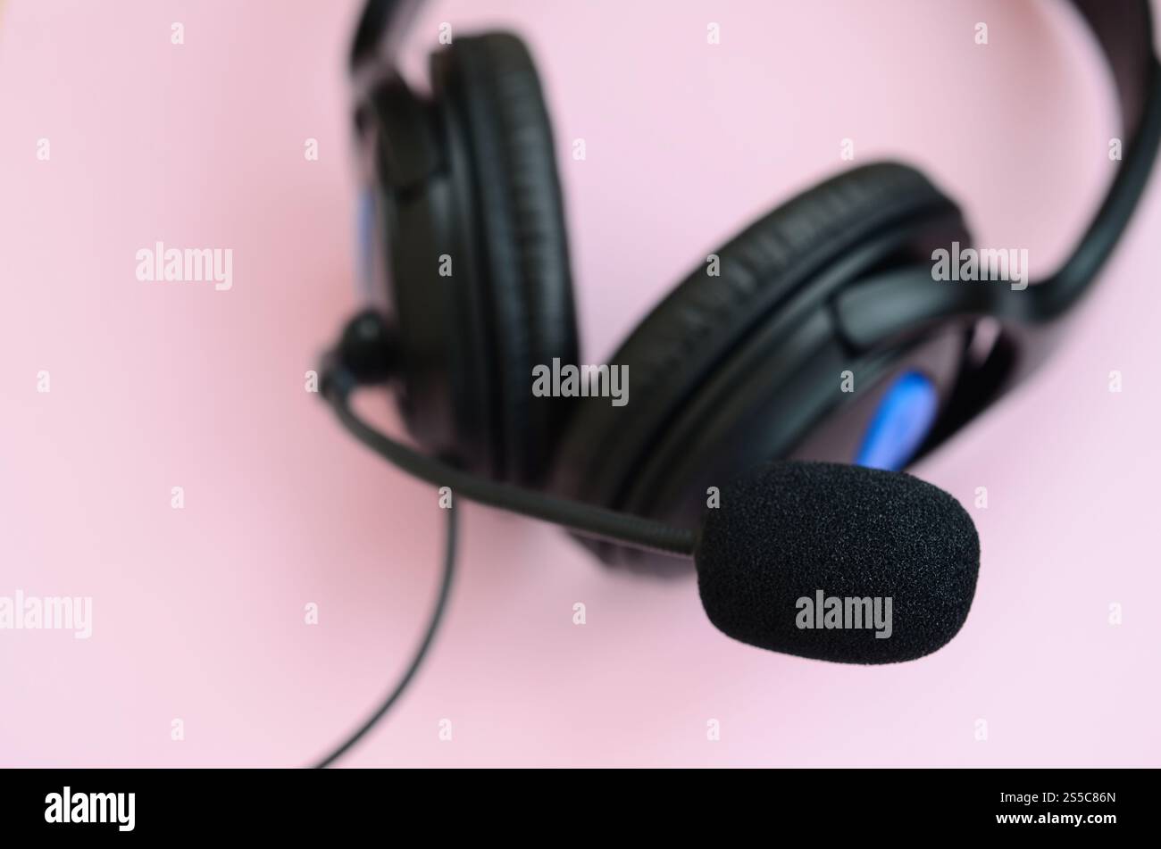 Le cuffie nere si trovano su un colorato sfondo rosa pastello. Concetto di ascolto musicale. Concetto di ascolto musicale. Le cuffie nere si trovano su sfondo rosa Foto Stock