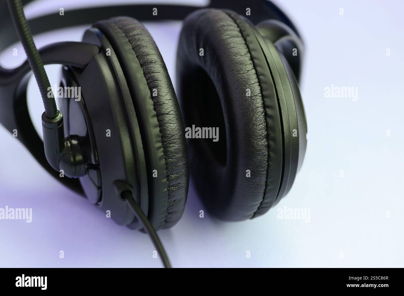 Le cuffie nere si trovano su un colorato sfondo viola pastello. Concetto di ascolto musicale. Concetto di ascolto musicale. Le cuffie nere si appoggiano al viola Foto Stock