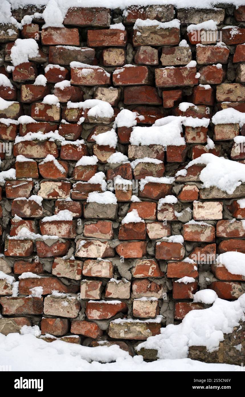 La consistenza della vecchia parete di mattoni, coperta da uno spesso strato di neve dopo una forte nevicata Foto Stock