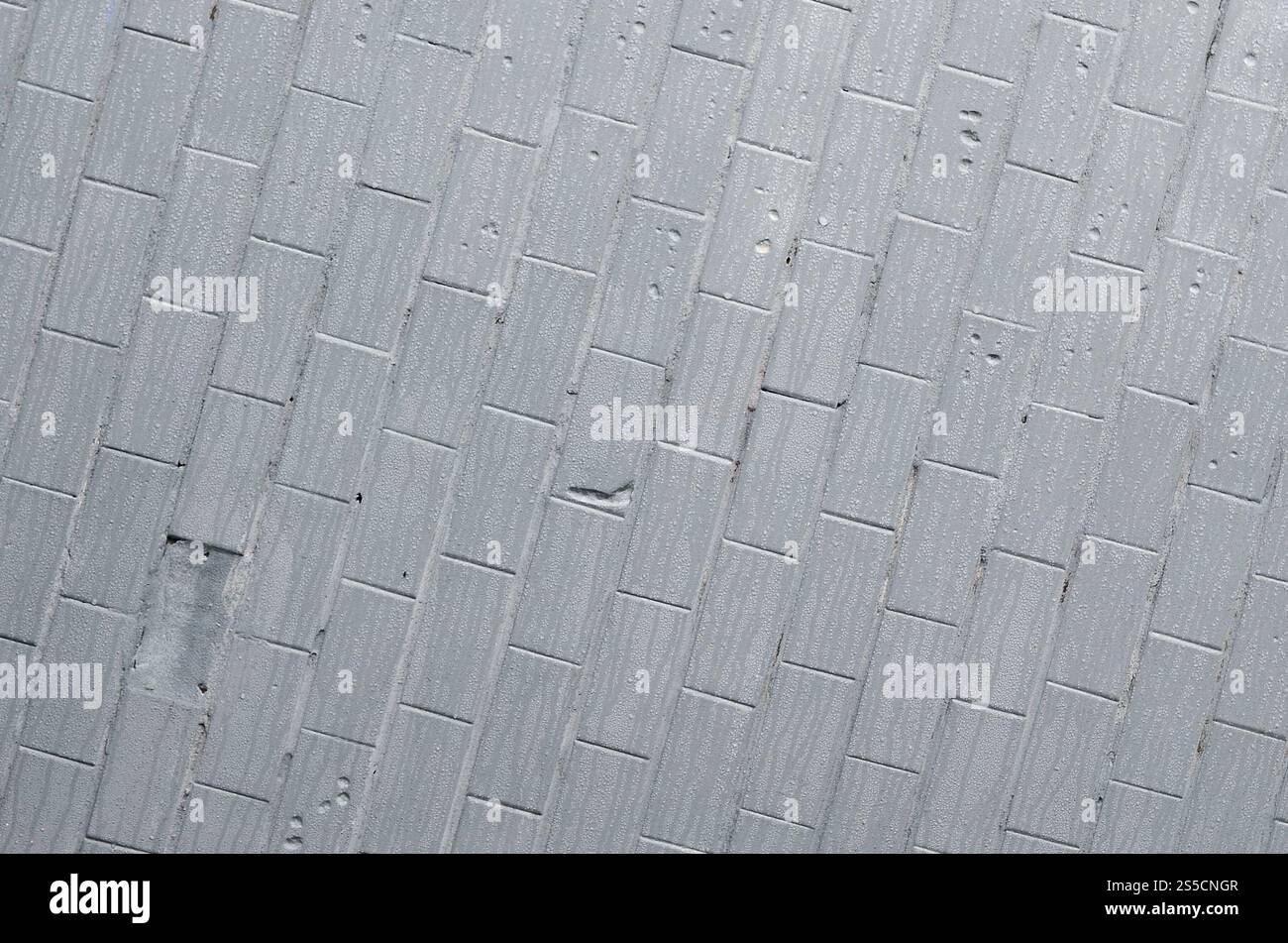 La struttura del muro dalla vecchia piastrella, dipinta di grigio sotto l'influenza della condensazione. Molte piccole gocce e macchie d'acqua sulla parete Foto Stock