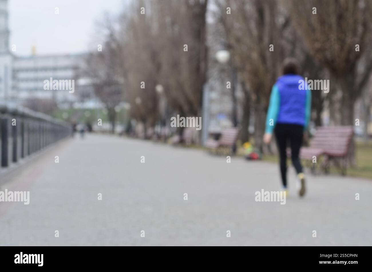 Paesaggio sfocato del parco primaverile vicino al lungomare. Strada davanti, decorata con alberi e una bassa recinzione dell'argine. Paesaggio sfocato di Foto Stock
