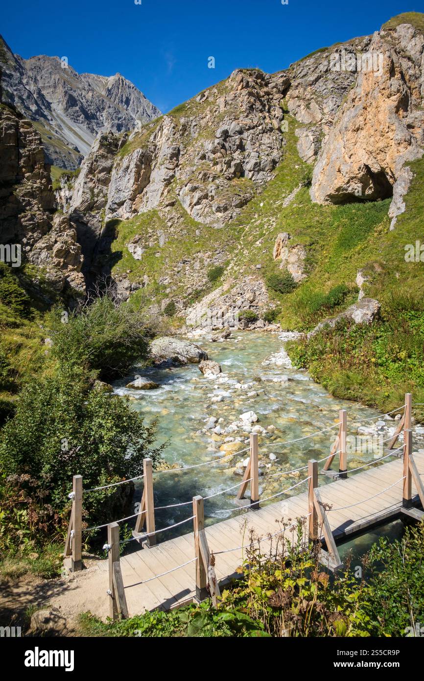 Fiume di montagna e ponte in legno nel Parco Nazionale della Vanoise Valle alpina, Savoia, alpi francesi. Fiume di montagna e ponte in legno nel Parco nazionale della Vanoise Foto Stock