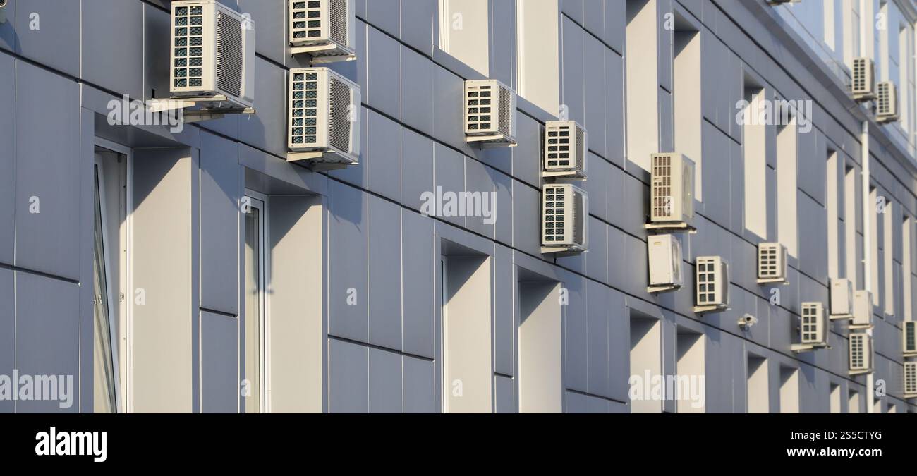 Parete grigia dell'edificio degli uffici in lamiera metallica con finestre e condizionatori d'aria Foto Stock