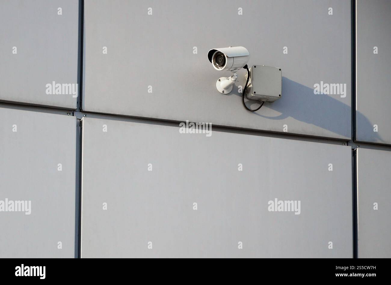 Telecamera di sorveglianza bianca integrata nella parete metallica dell'edificio degli uffici Foto Stock