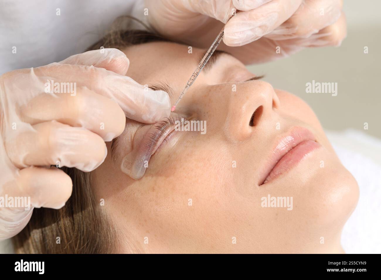 Procedura di laminazione delle ciglia. Estetista che attacca le ciglia della donna per immergerle nel salone di bellezza, primo piano Foto Stock