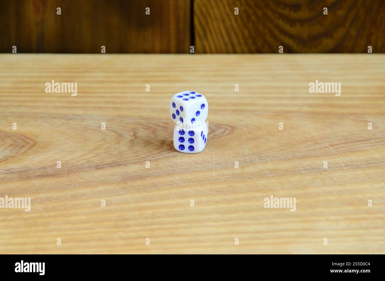 Alcuni dadi giacciono sulla superficie di legno naturale. Elementi per generare numeri da uno a sei sotto forma di punti dipinti sul lato di Foto Stock