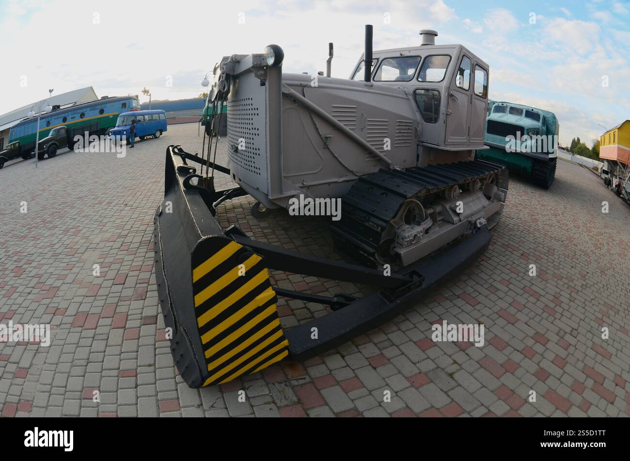 Foto di un bulldozer grigio tra i convogli ferroviari. Forte distorsione dalla lente fisheye Foto Stock