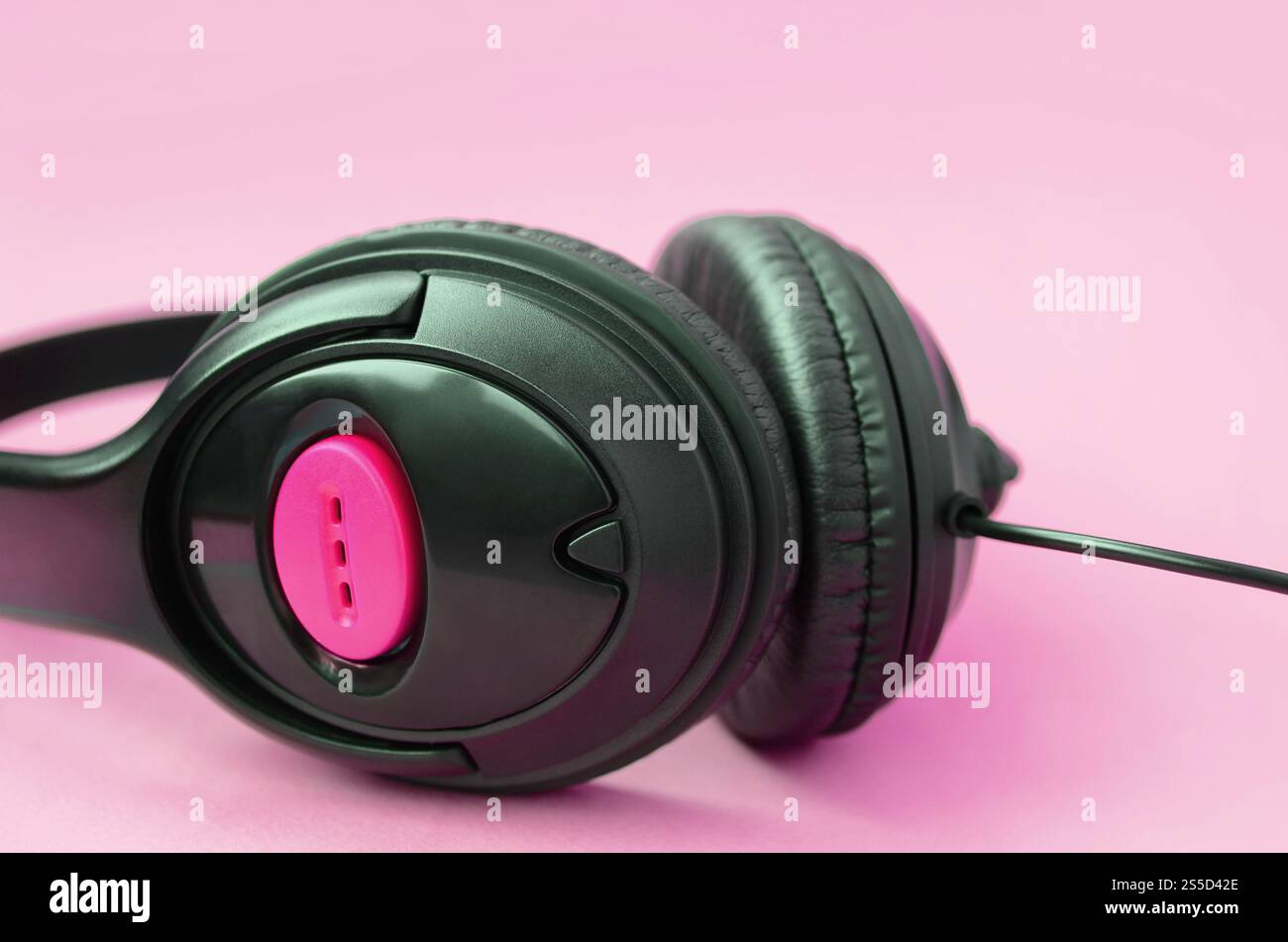 Le cuffie nere si trovano su un colorato sfondo rosa pastello. Concetto di ascolto musicale. Concetto di ascolto musicale. Le cuffie nere si trovano su sfondo rosa Foto Stock