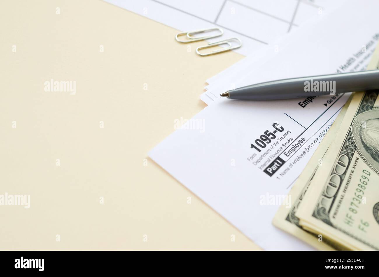 Modulo IRS 1095-C datore di lavoro-fornito offerta di assicurazione sanitaria e copertura tassa in bianco giace con penna e molte centinaia di banconote di dollari sulla pagina del calendario. Tassa Foto Stock