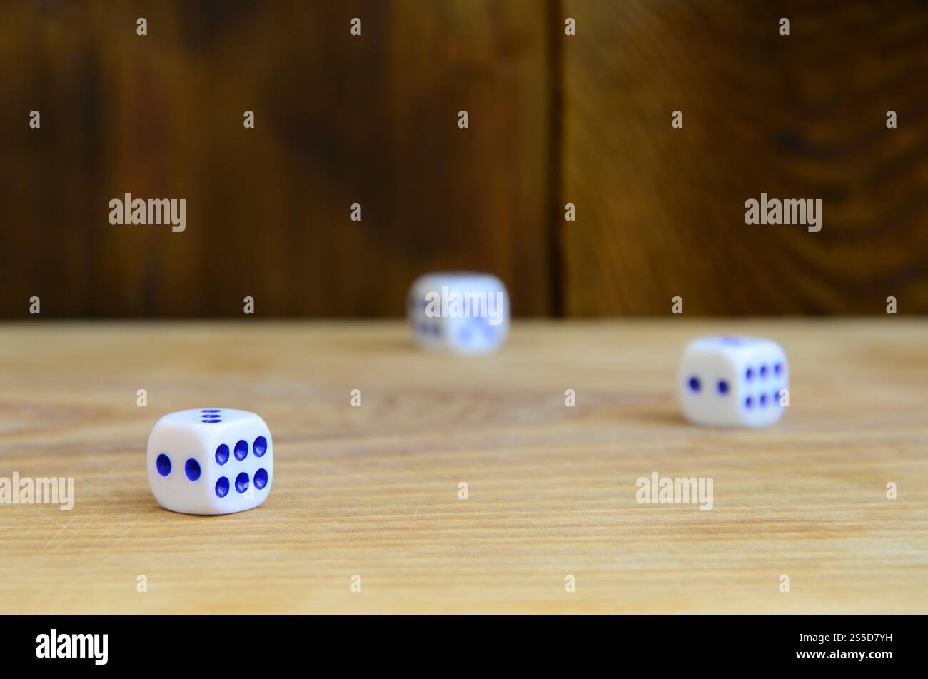 Alcuni dadi giacciono sulla superficie di legno naturale. Elementi per generare numeri da uno a sei sotto forma di punti dipinti sul lato di Foto Stock