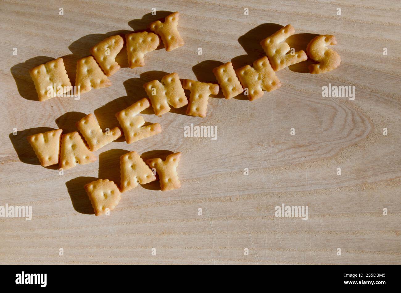Buon San Valentino. Testo dai cracker salati come lettere inglesi stampate che giacciono su un tagliere di legno. Messaggio, allineato con commestibile Foto Stock