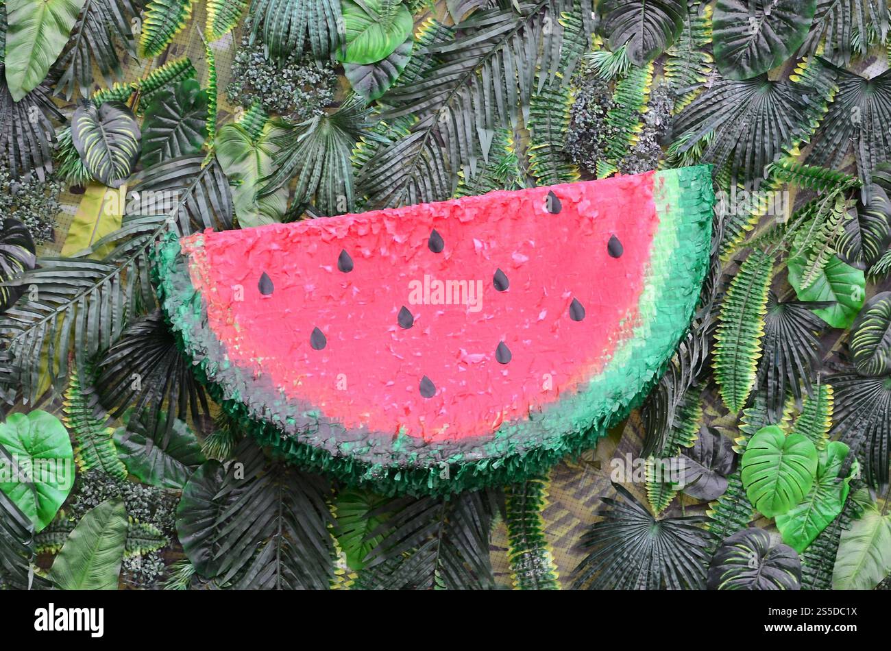 Motivo tropicale con foglie di giungla e fondo floreale di frutta anguria. Fetta di anguria di plastica con foglia di palma. Motivo tropicale con giungla Foto Stock