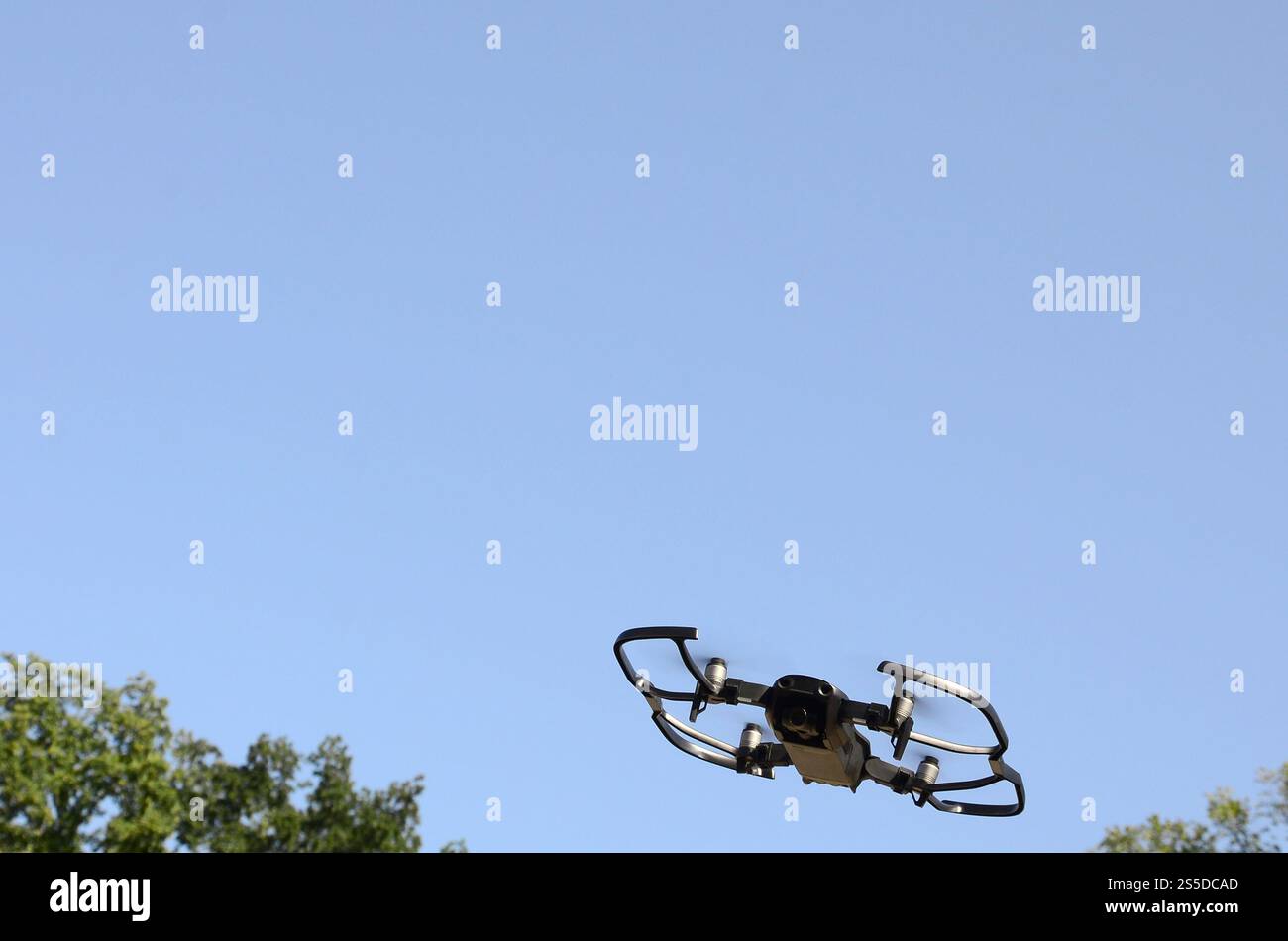 Drone con fotocamera decolla dalla terraferma e vola per scattare foto aeree al tramonto davanti agli alberi. Drone con fotocamera decollo da Foto Stock