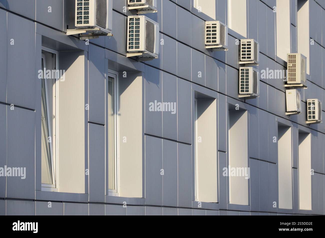 Parete grigia dell'edificio degli uffici in lamiera metallica con finestre e condizionatori d'aria Foto Stock